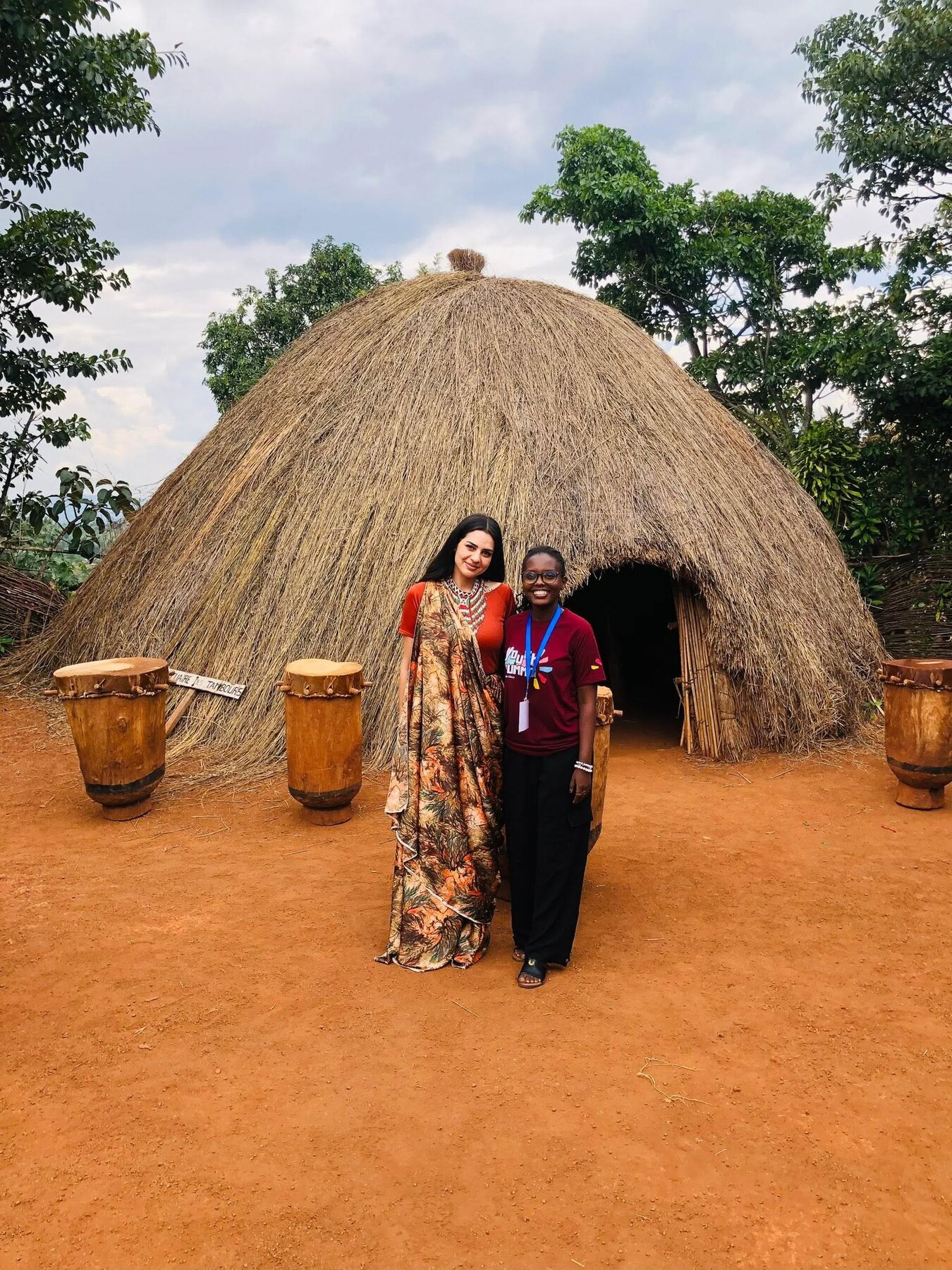 Traveler and local guide outside the traditional royal hut at Gishora